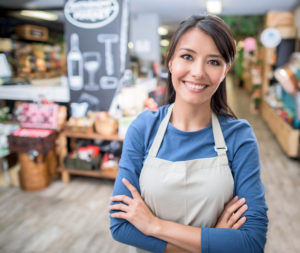 Latin woman working at a supermarket and wearing an apron as she's looking at the camera smiling
