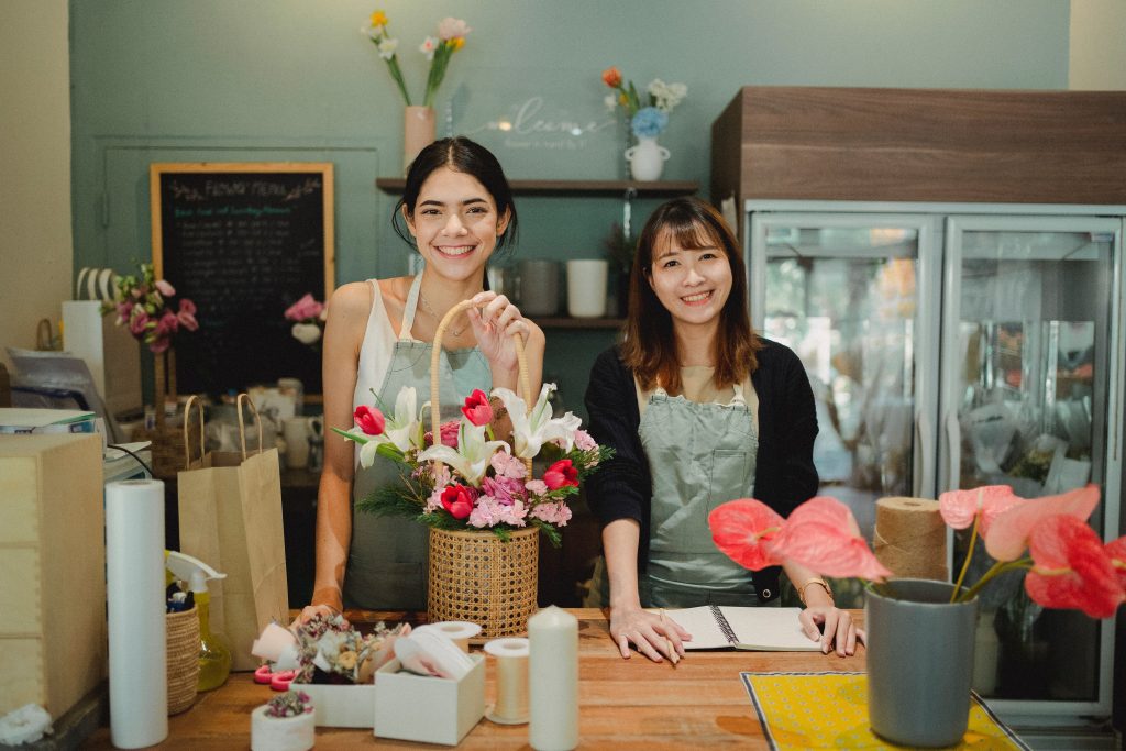 Two women in a florist shop smiling at the camera. Chose this picture to represent small business owners and managers.